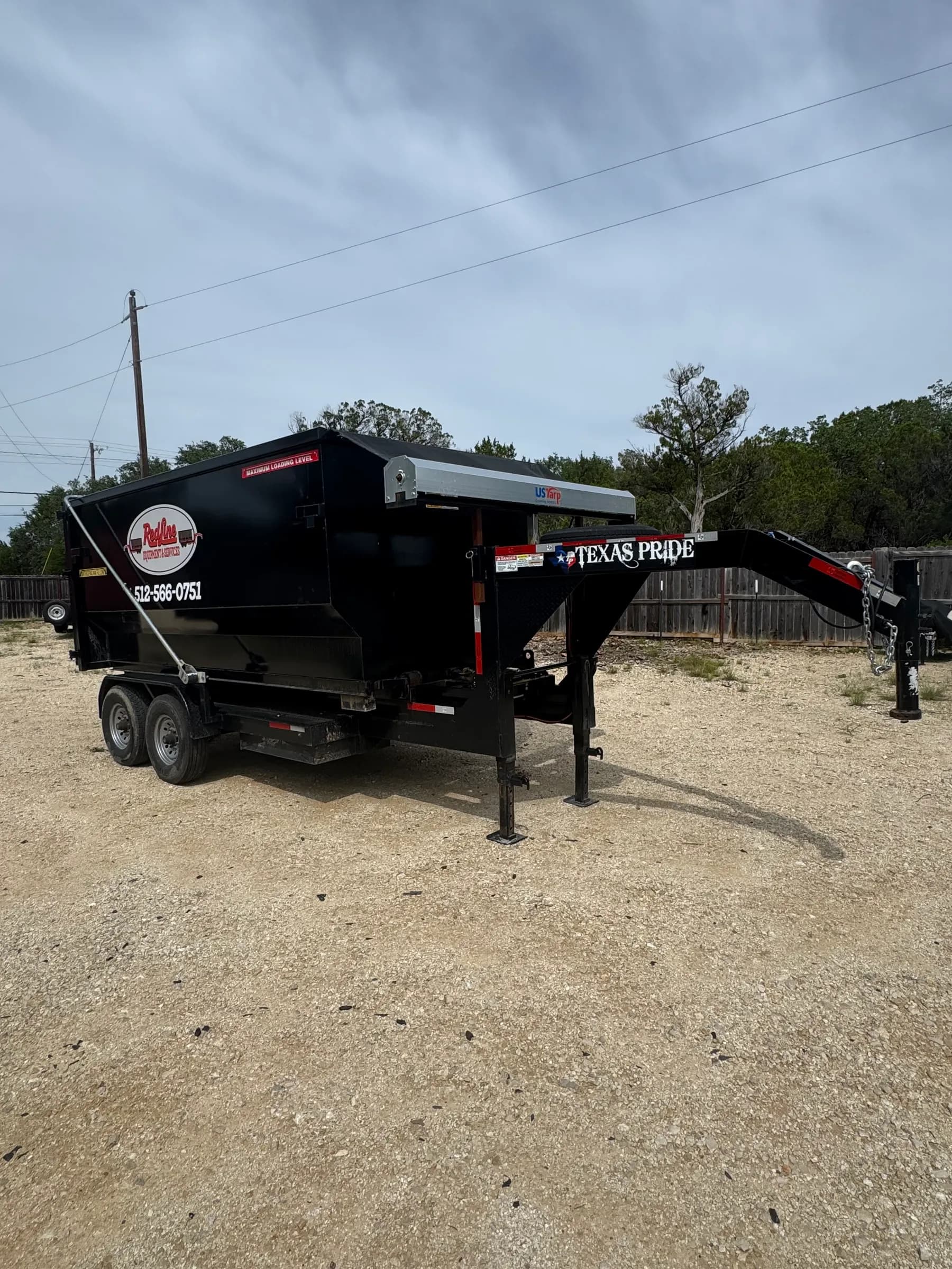 RedLine Dumpsters black roll-off container trailer with Texas Pride logo on gravel surface