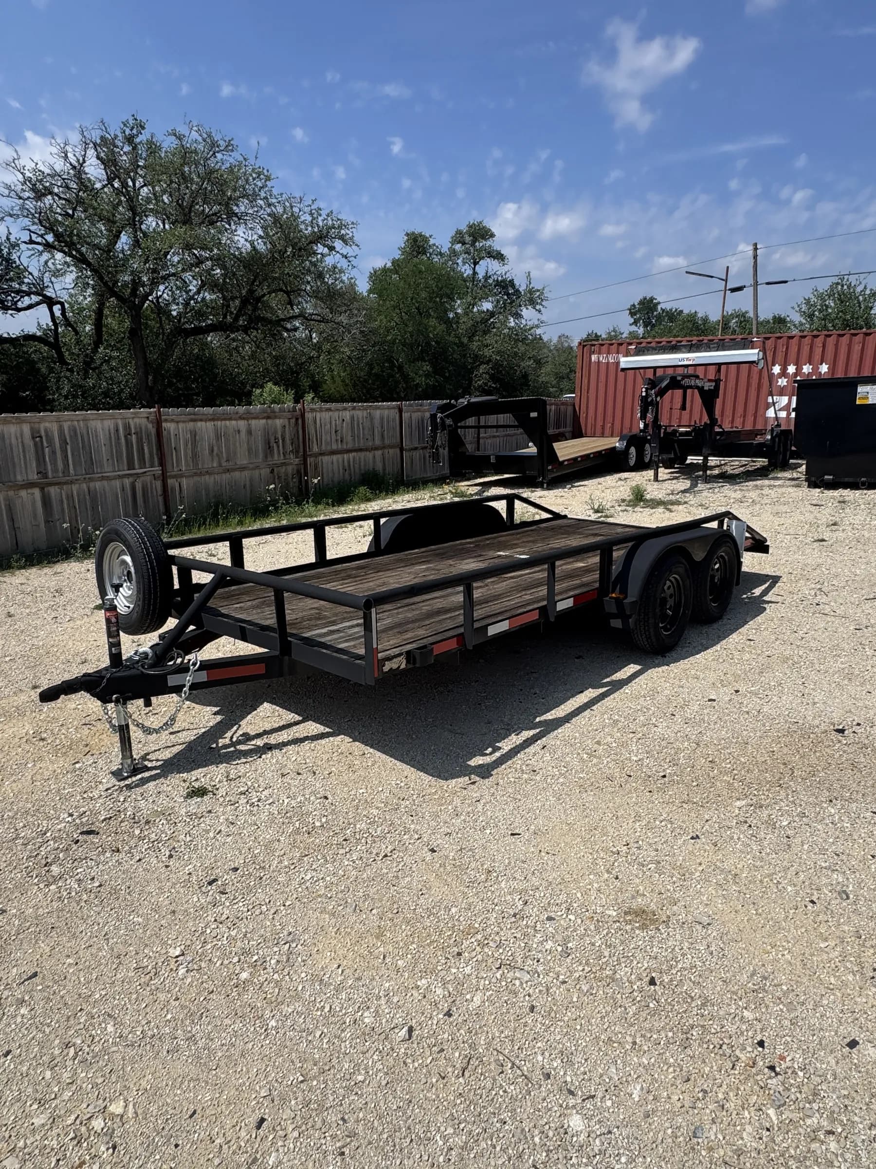16-foot utility trailer with wood deck and side rails on the RedLine rental lot
