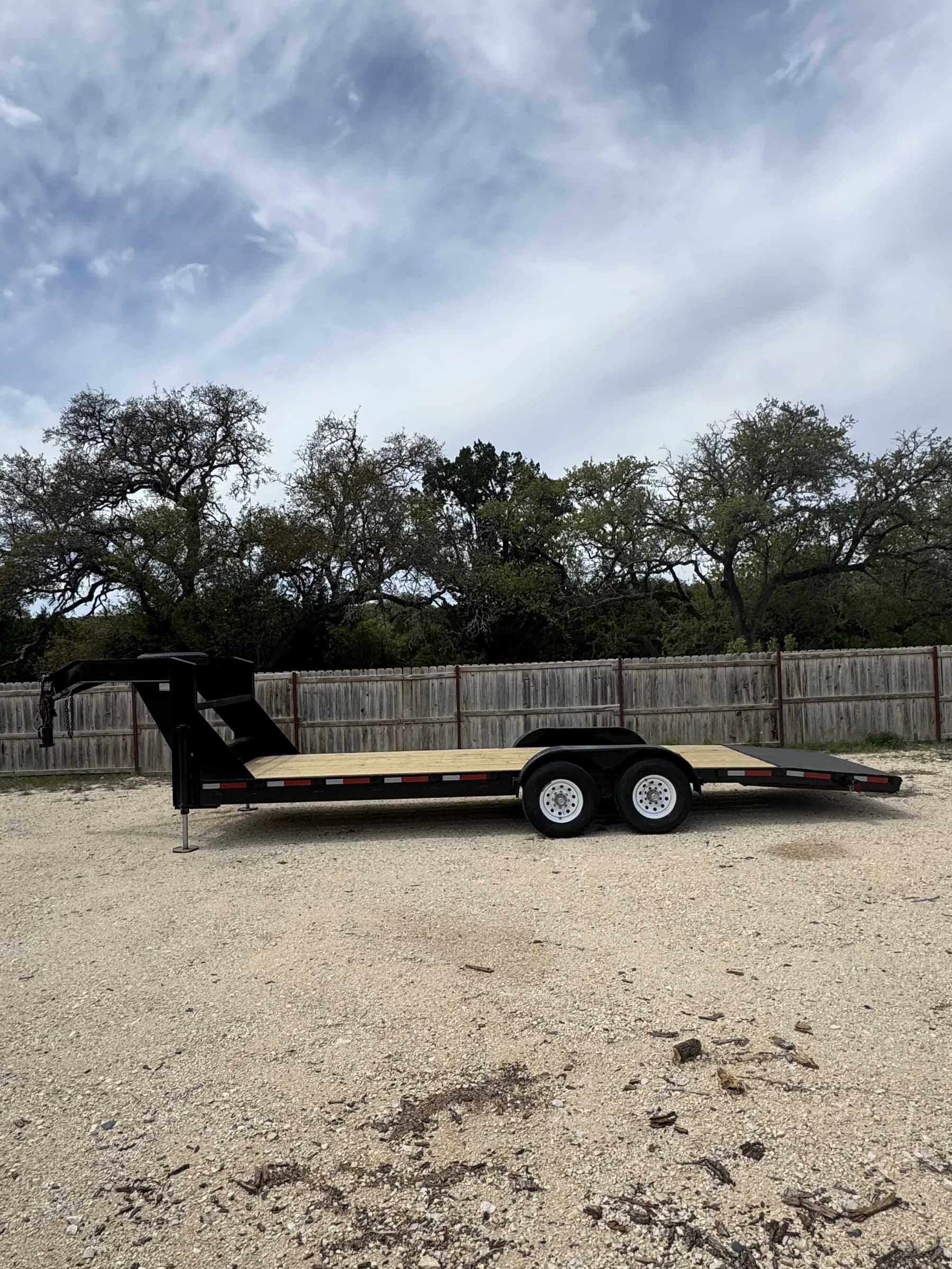 24-foot gooseneck trailer with wood deck on the gravel RedLine rental lot