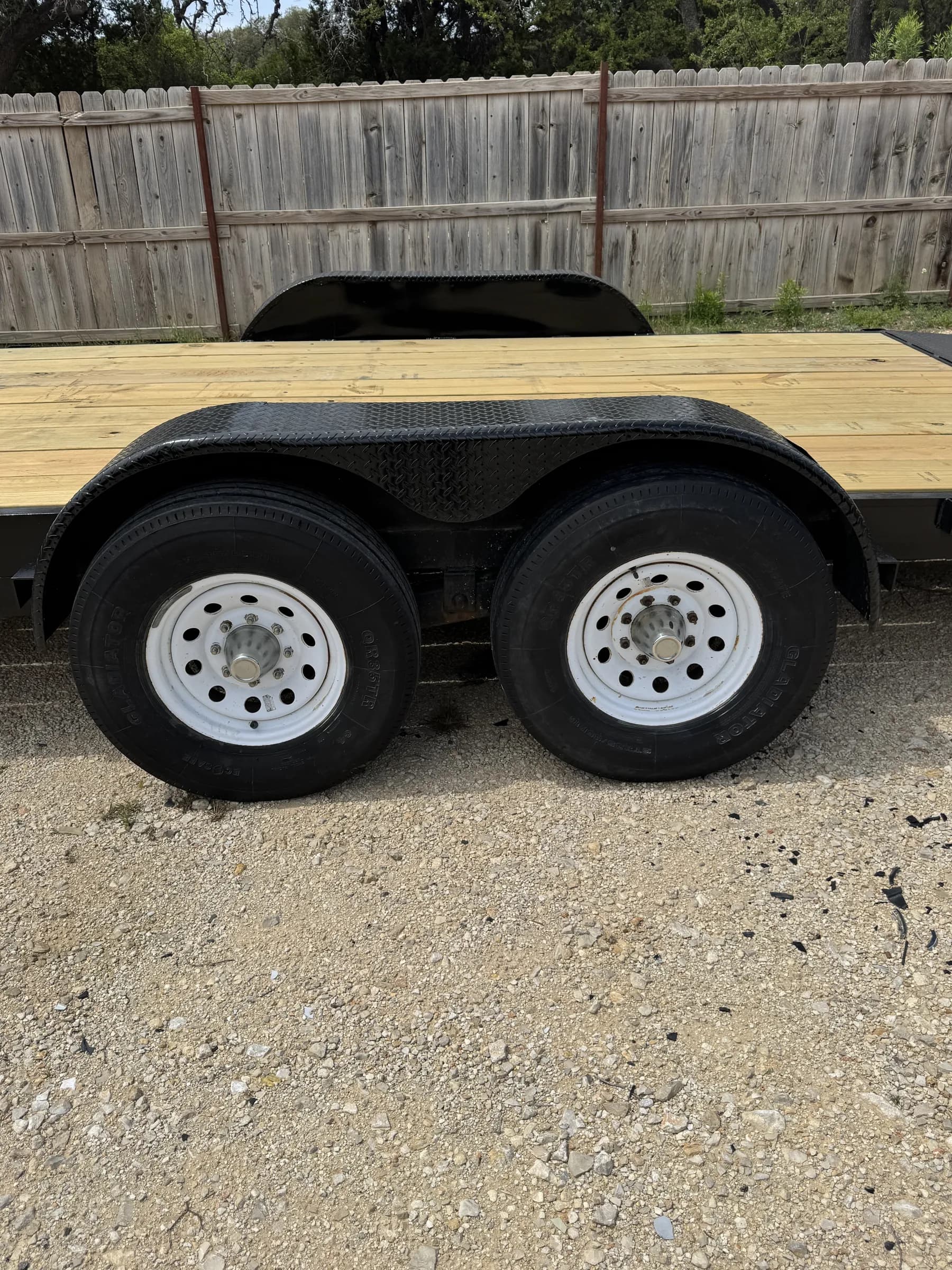 Dual axle wheels and wooden deck close-up on the RedLine 24-foot gooseneck trailer