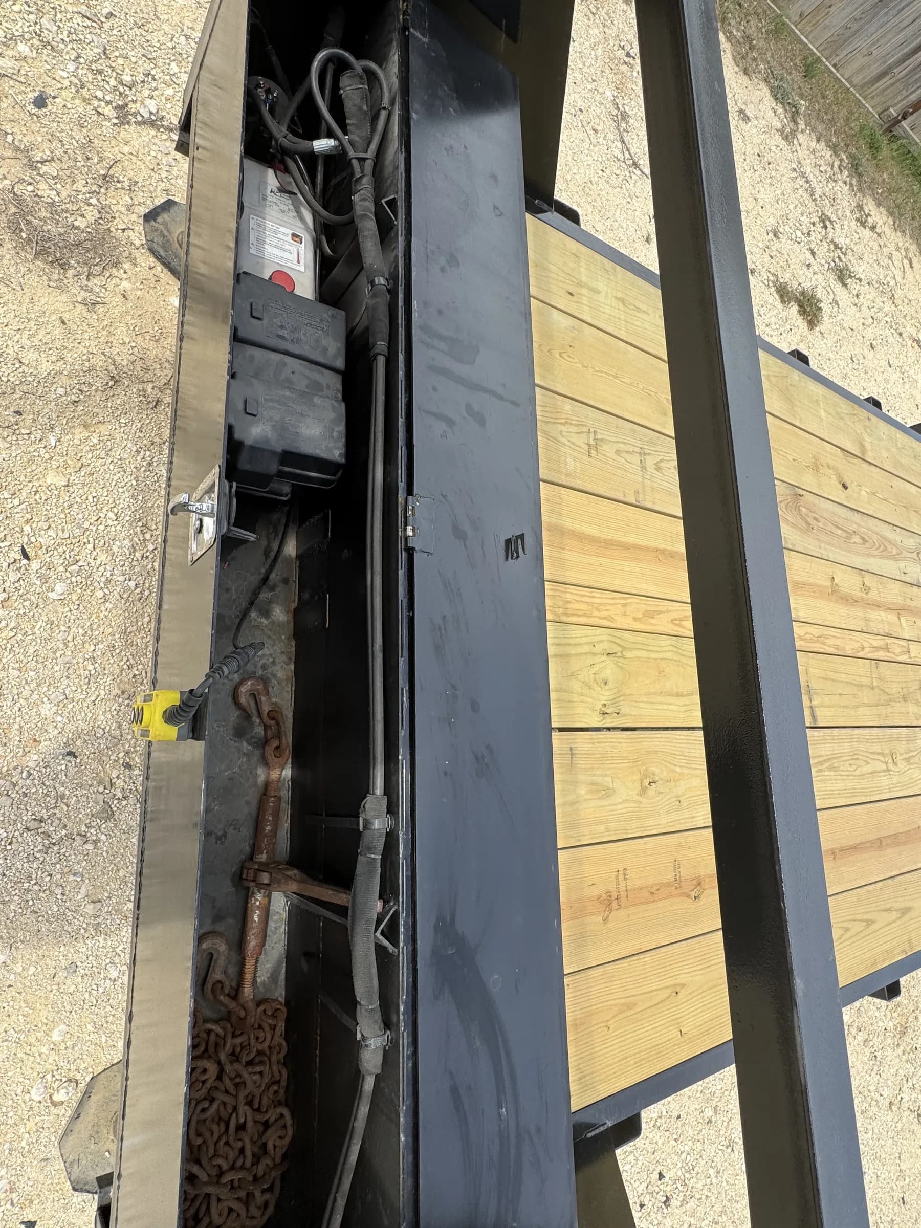 Open storage compartment showing hydraulic system and chains on the RedLine 24-foot gooseneck