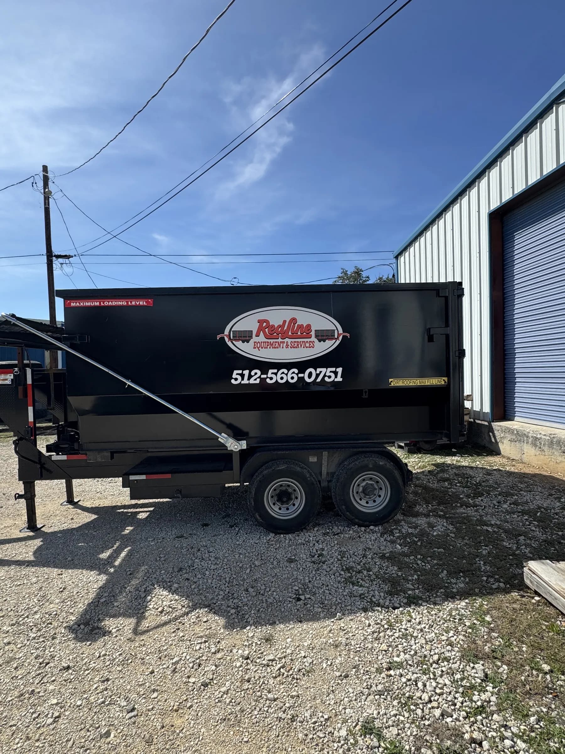 RedLine Equipment & Services black dumpster trailer rental on the gravel lot