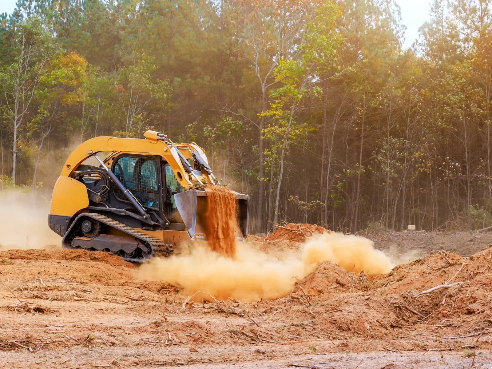 RedLine skid steer dumping a bucket of dirt while clearing a Hill Country construction site
