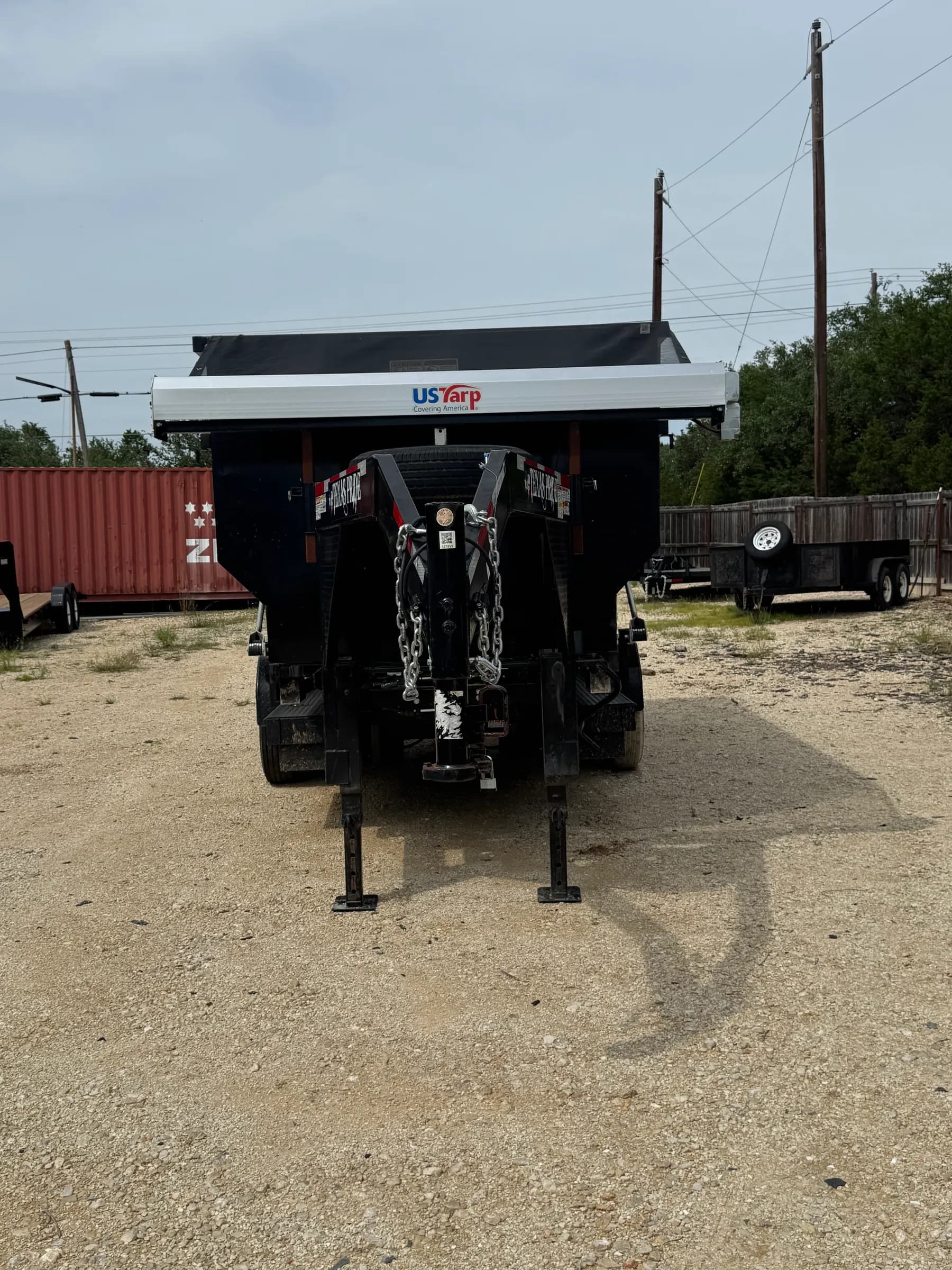US Tarp black gooseneck dump trailer with hydraulic lift system at trailer dealership lot