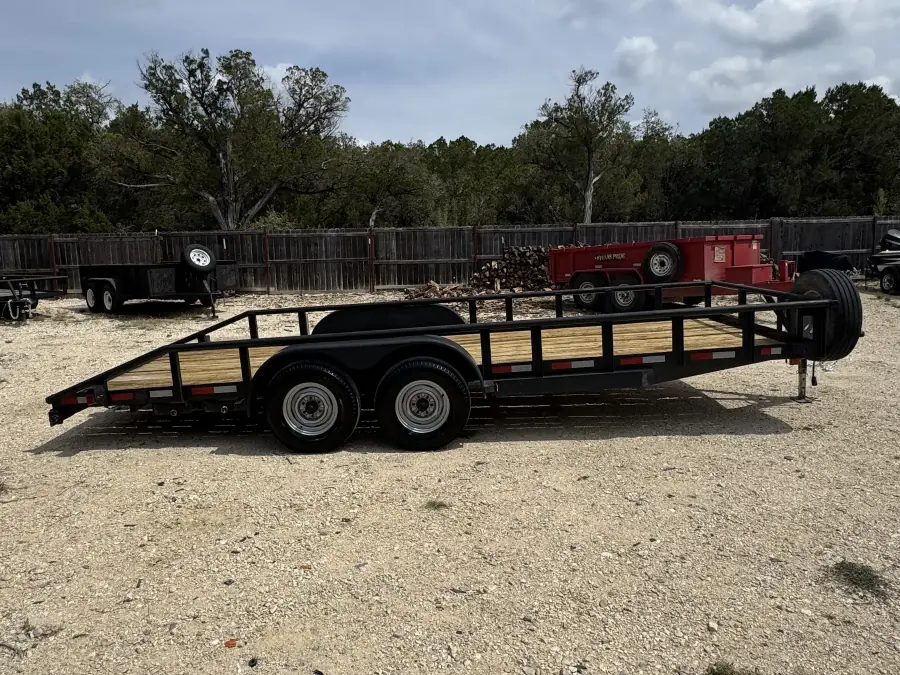 20-foot black tandem axle utility trailer with wood deck and side rails on the RedLine rental lot