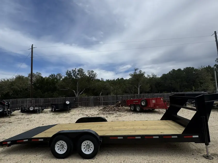 24-foot gooseneck flatbed trailer with wood deck at RedLine rental lot under a dramatic sky