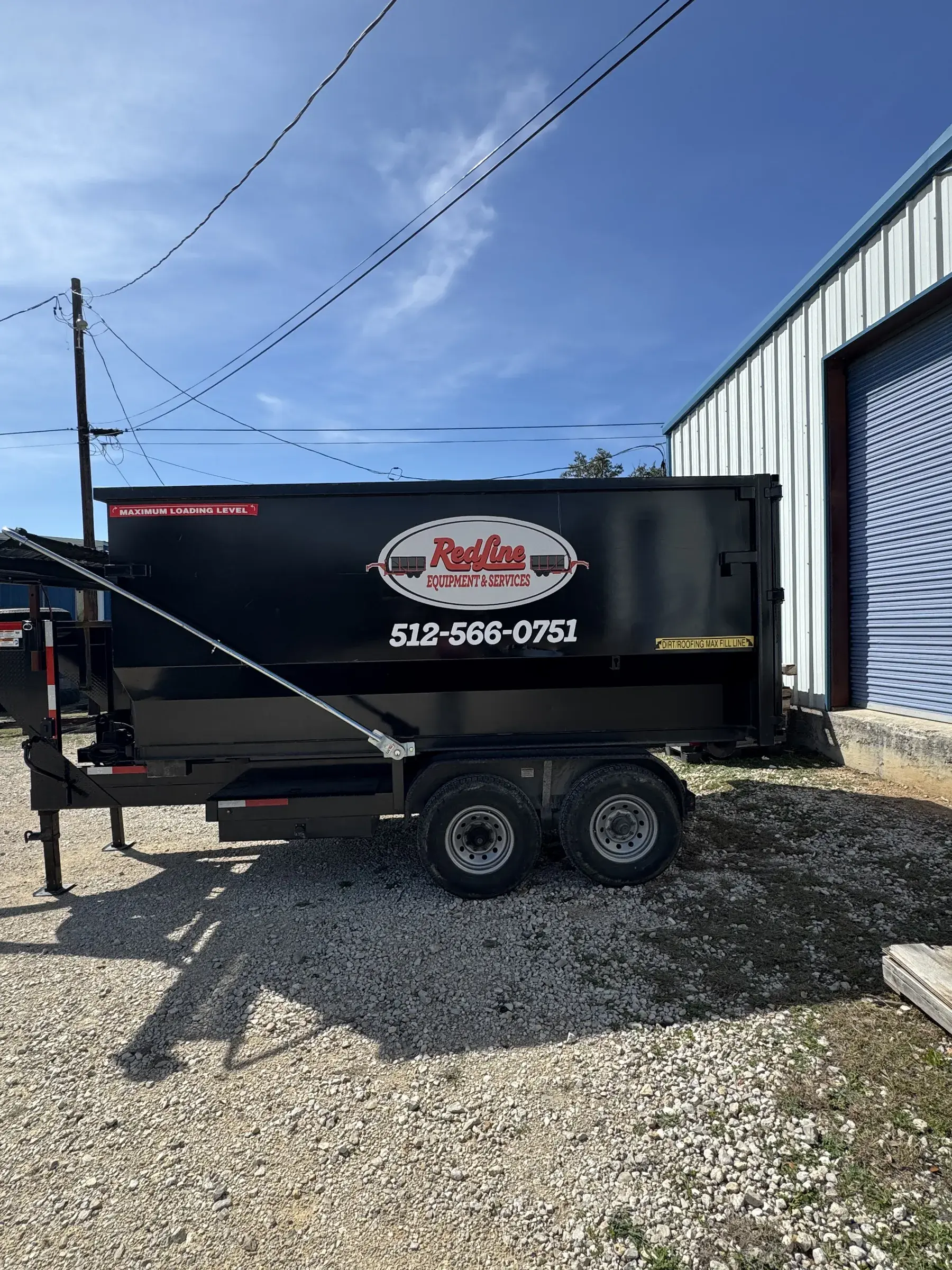 RedLine Equipment & Services black dumpster trailer rental on the gravel lot
